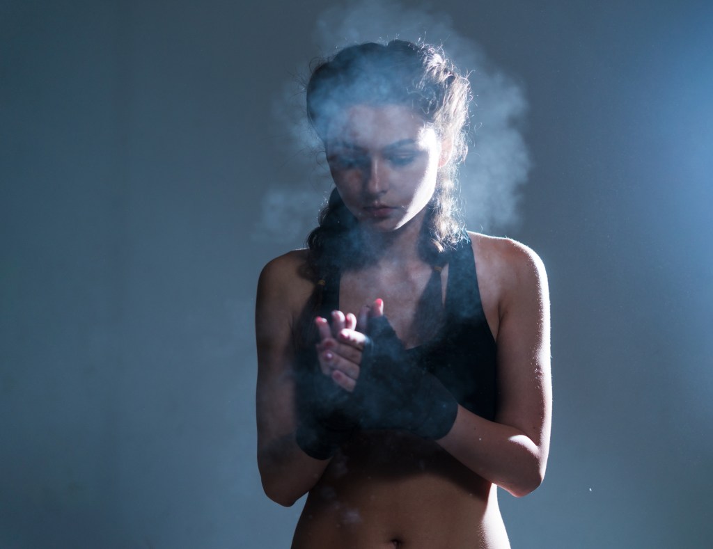 mulher boxeadora usando luvas e trança boxe em um fundo escuro | treinar boxe sem saco de areia
