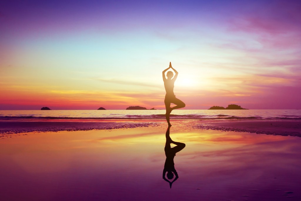 Mulher fazendo pose de ioga na praia