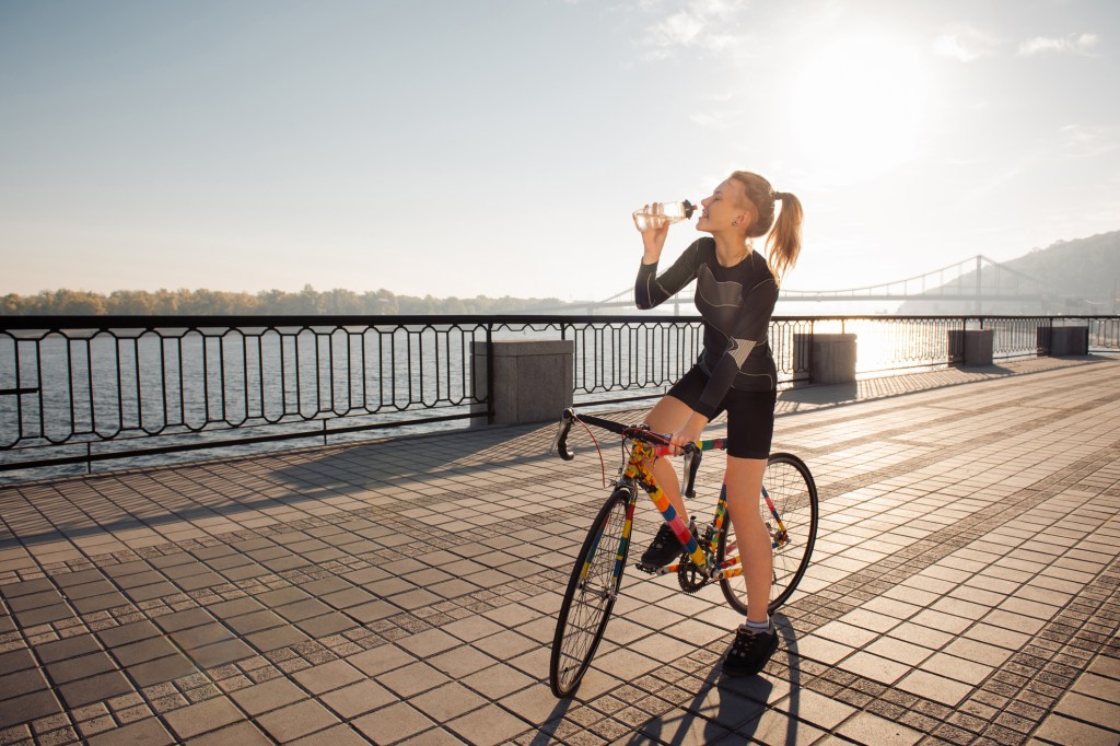 Mulher de bike bebendo água