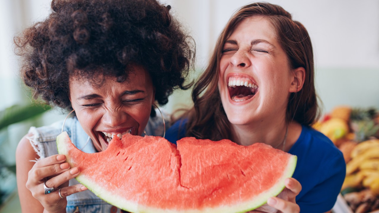 Mulheres rindo e comendo melancia