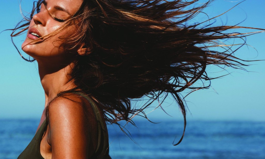 Mulher na praia com cabelos ao vento