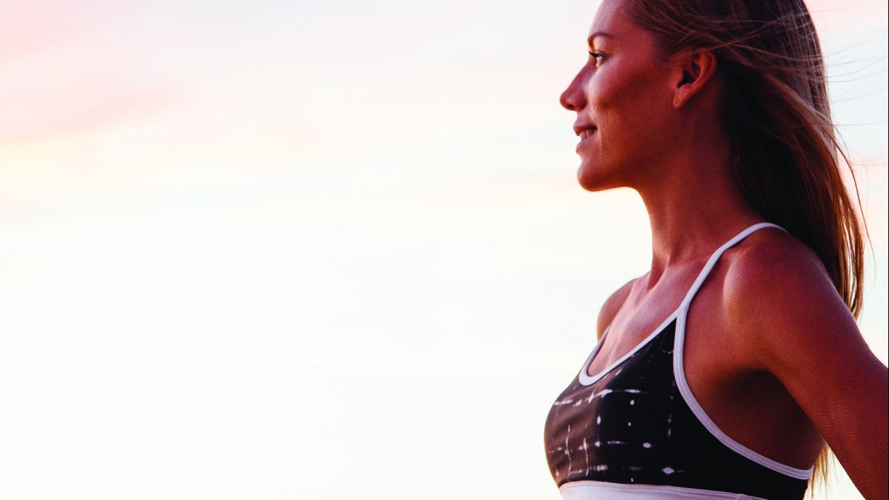 Mulher com roupa de ginástica olhando o horizonte