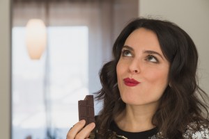 Beautiful young brunette with long hair eating chocolate