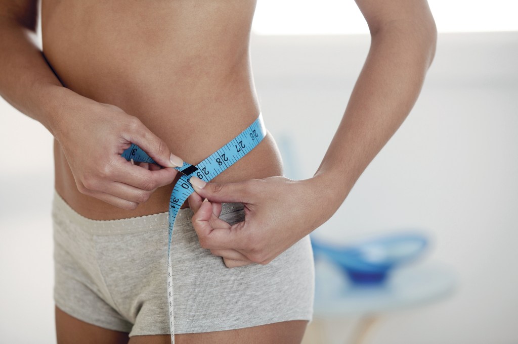 Mulher medindo cintura com fita métrica