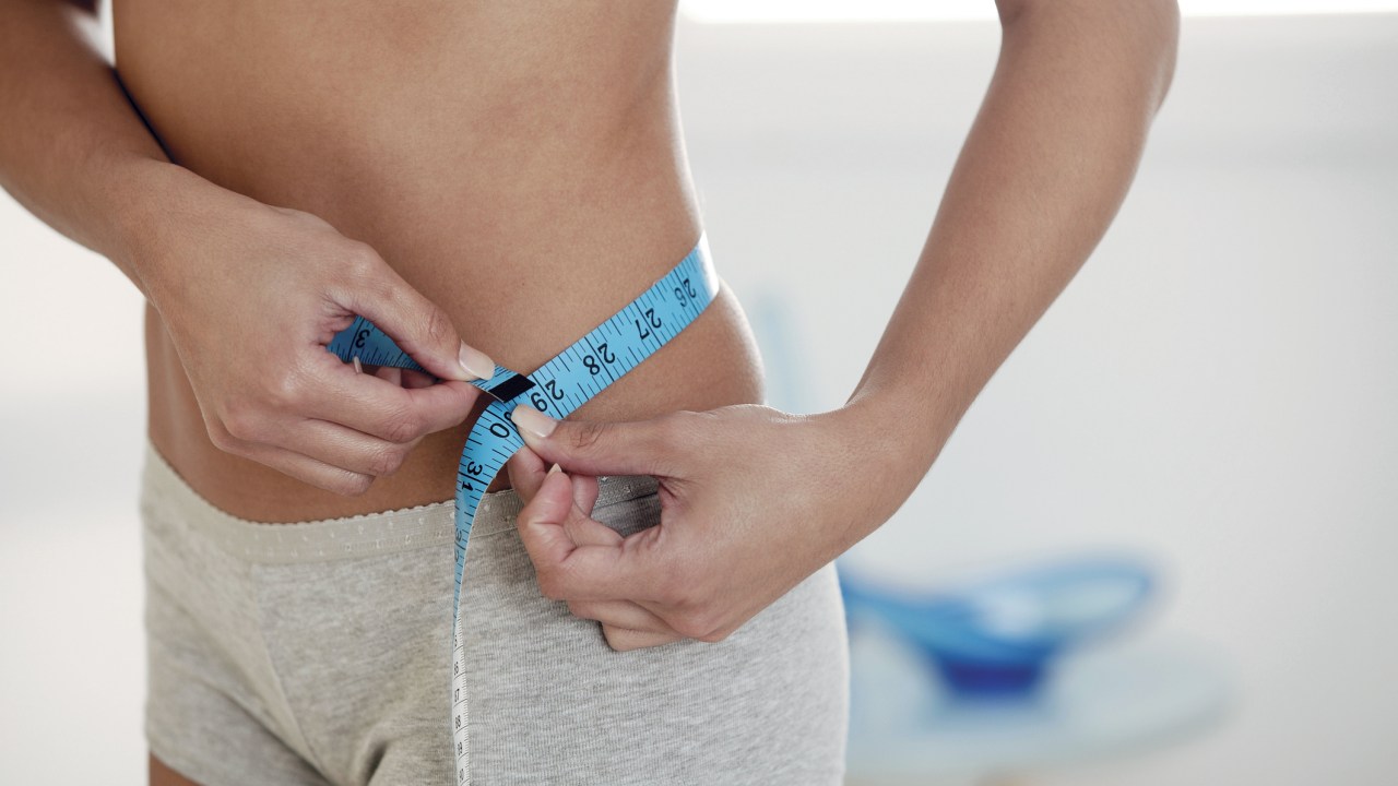 Mulher medindo cintura com fita métrica
