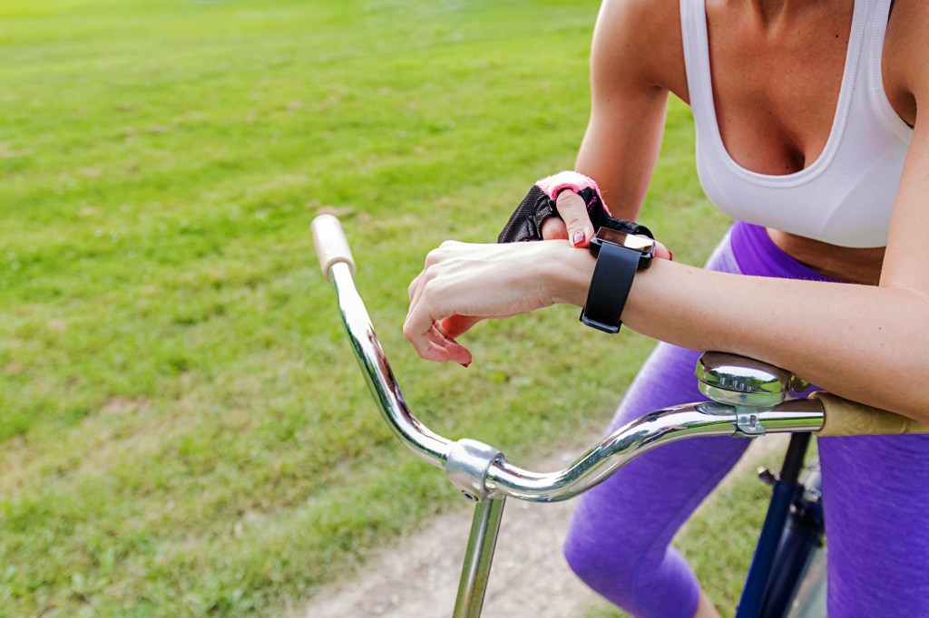 Mulher andando de bicicleta e checando relógio de pulso
