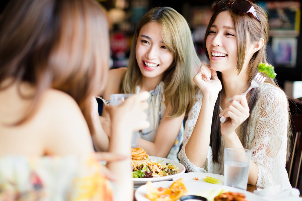 Três amigas asiáticas comendo num, restaurante
