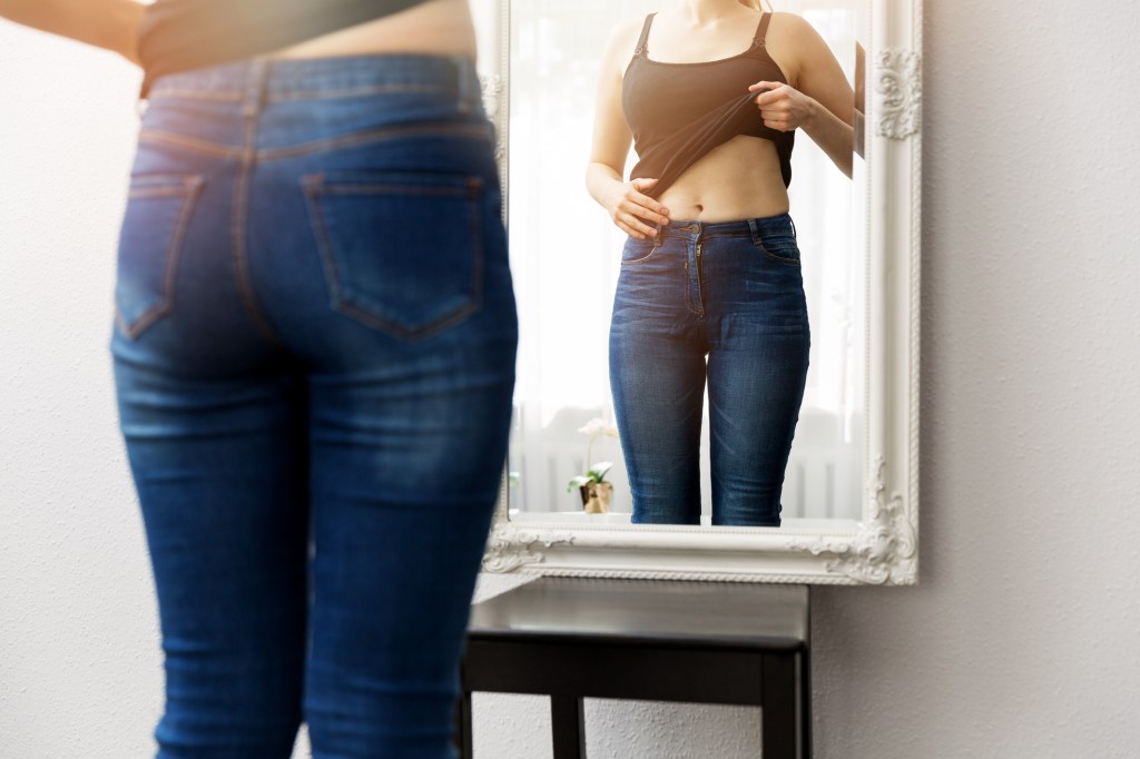Mulher olhando seu corpo em frente ao espelho