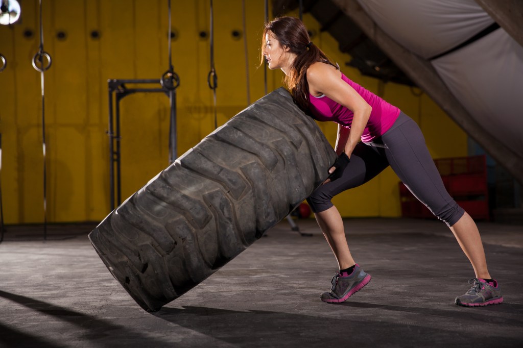 Mulher virando pneu no treino de crossfit - Como funcionam os treinos boot camp