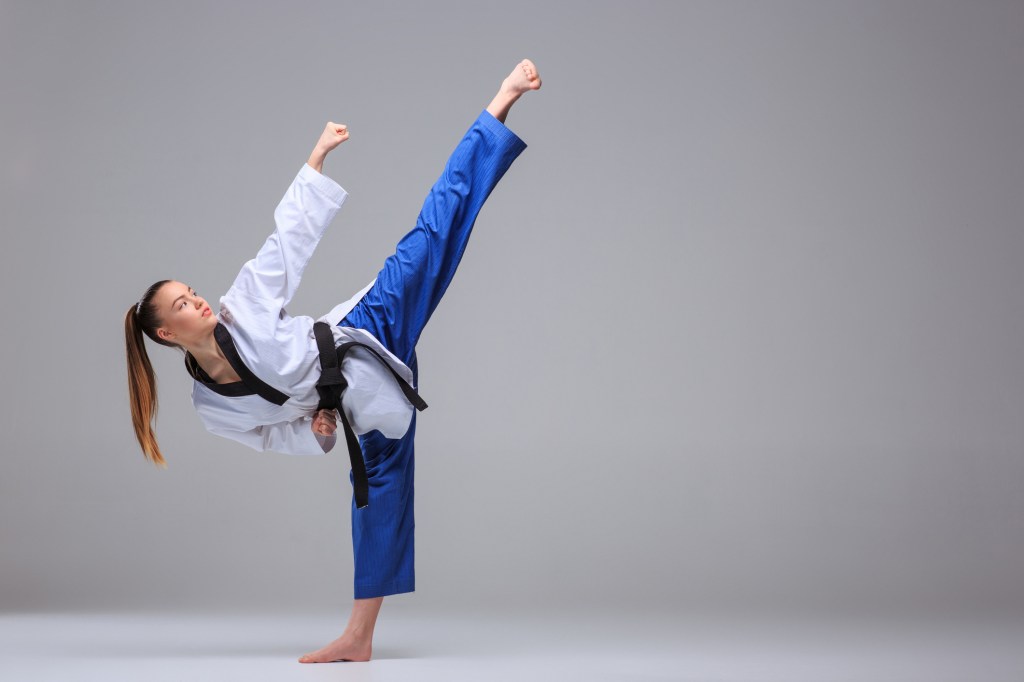 Mulher fazendo movimento de luta - artes marciais que fortalecem as pernas