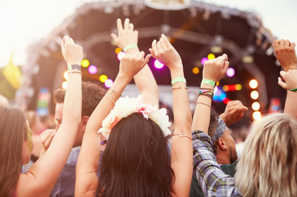 Mulheres assistindo a um festival de música com as mãos levantadas