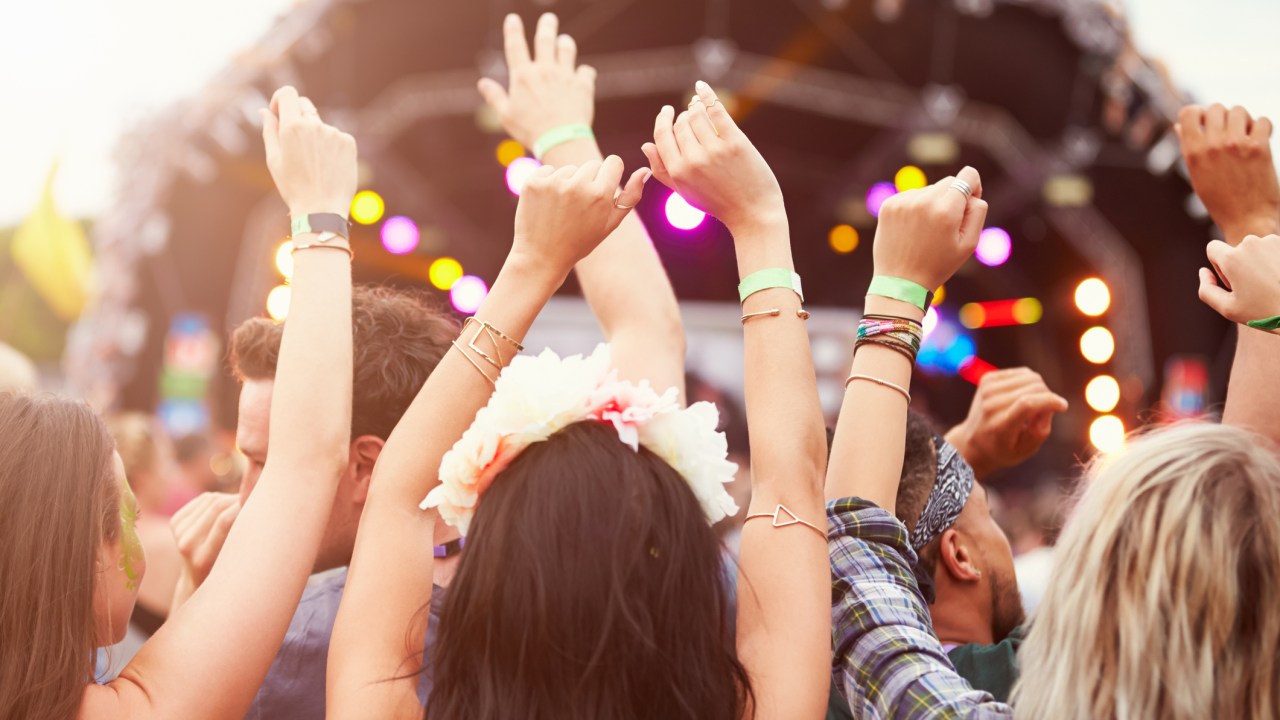 Mulheres assistindo a um festival de música com as mãos levantadas