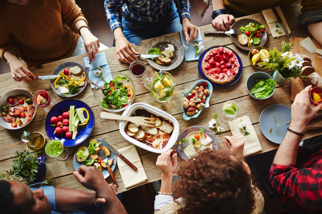 Grupo de amigos sentados à mesa com comida saudável