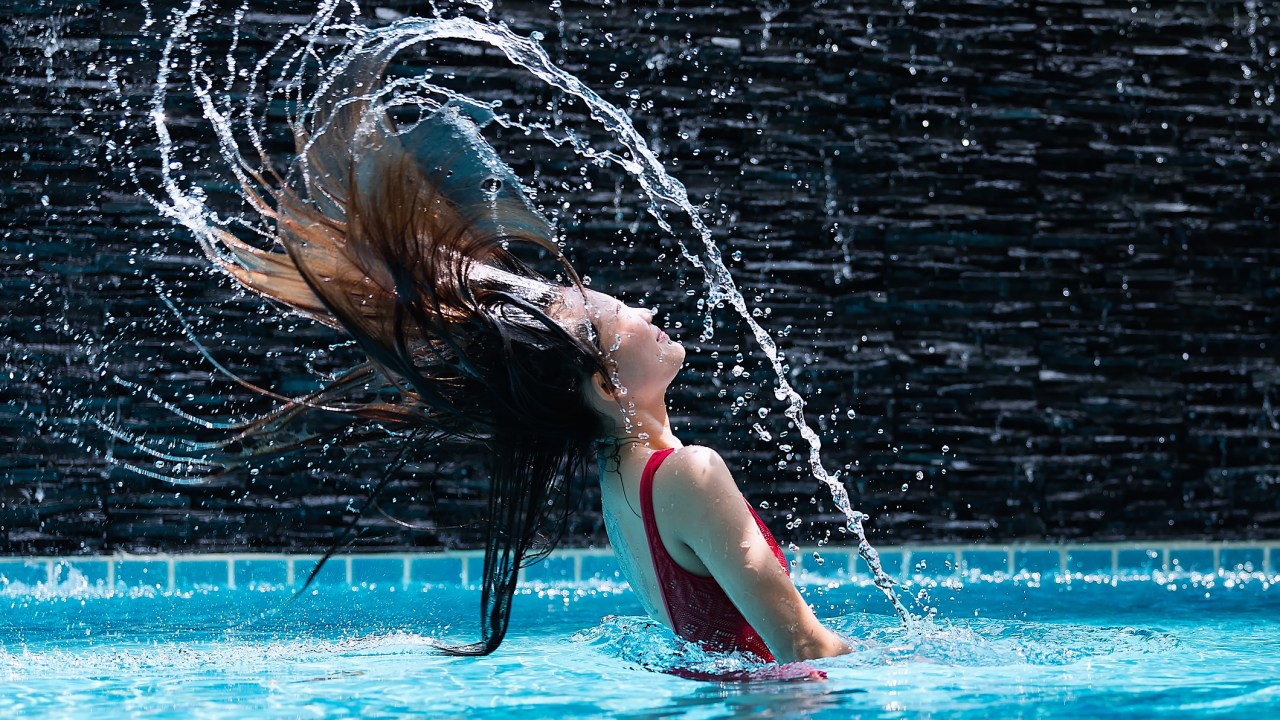 Mulher na piscina jogando o cabelo para o alto