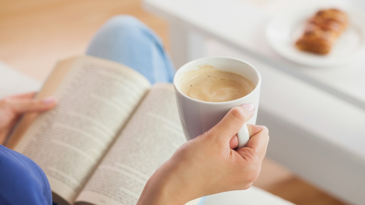 Mulher lendo e tomando café