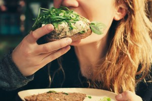 Girl biting veggie sandwich.