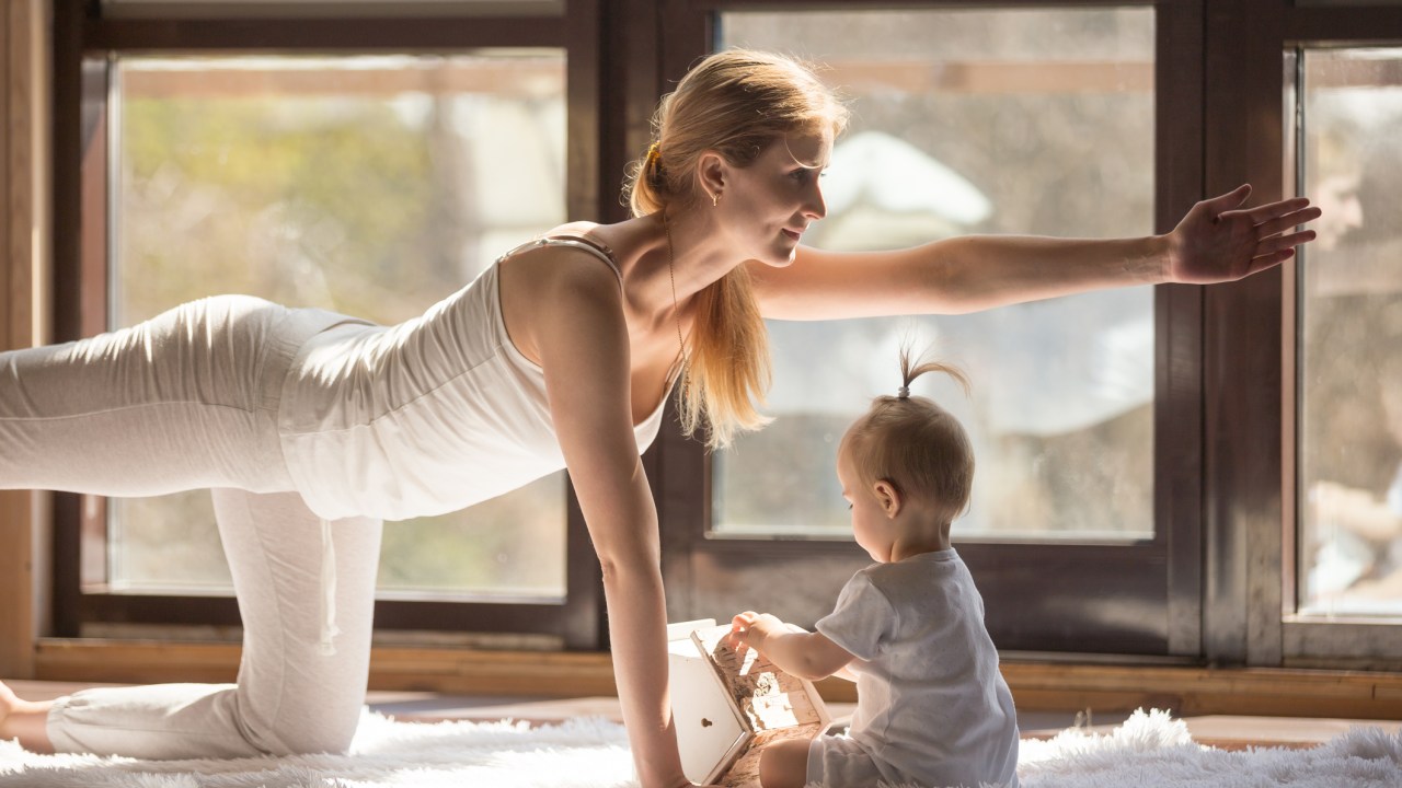 Mulher fazendo ioga com bebê do lado