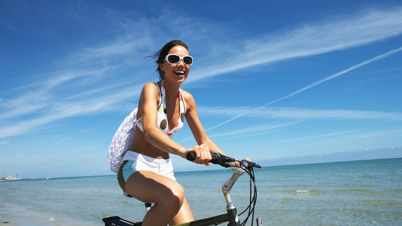 Mulher andando de bicicleta na praia