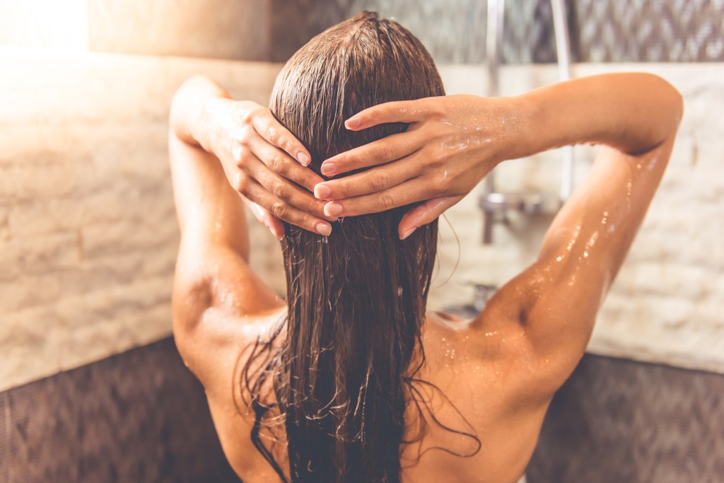 Mulher no banheiro lavando o cabelo durante o banho