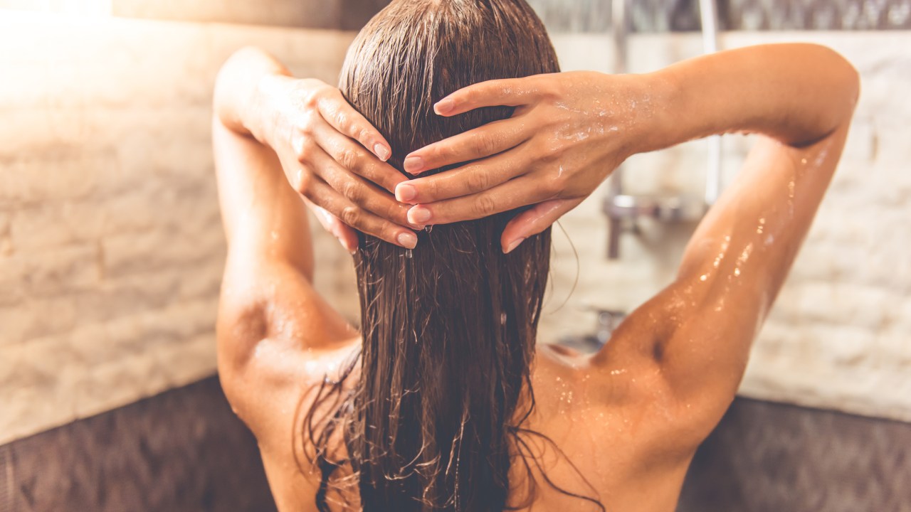 Mulher no banheiro lavando o cabelo durante o banho