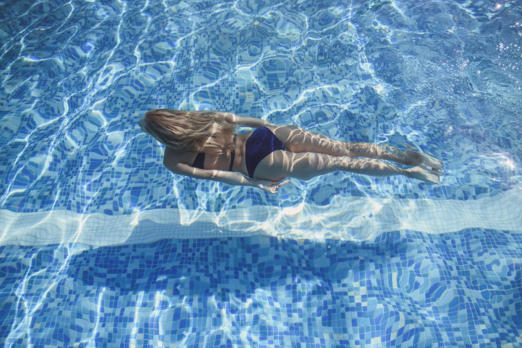 Mulher loira nadando dentro na piscina