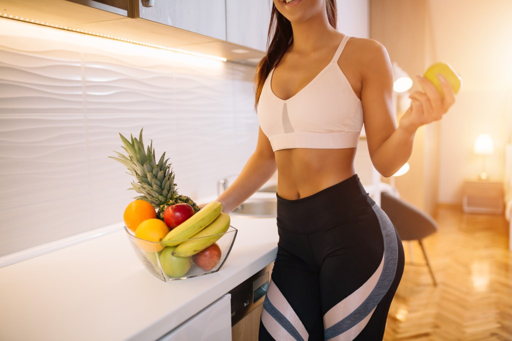 Mulher com roupa fitness na cozinha