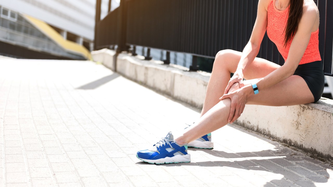 Mulher corredora com dor na perna - Estratégias para prevenir cãibras em uma prova de corrida