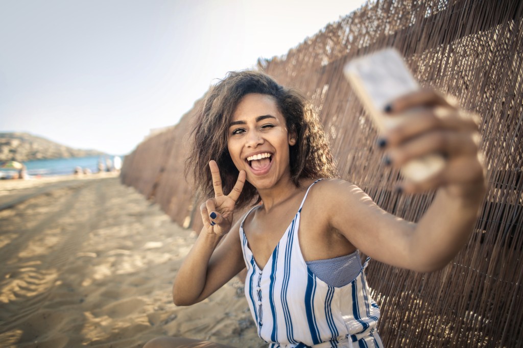 Mulher tirando uma selfie sorrindo na praia