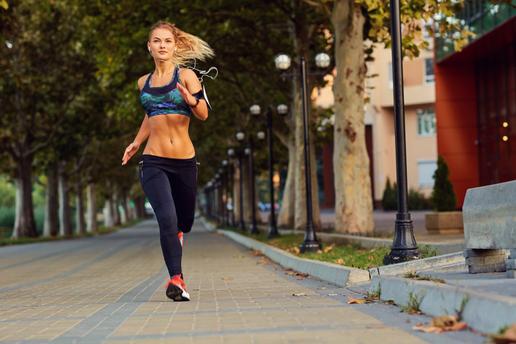 Imagem meramente ilustrativa mostra uma mulher loira correndo ao ar livre para ilustrar exercícios para pernas e bumbum
