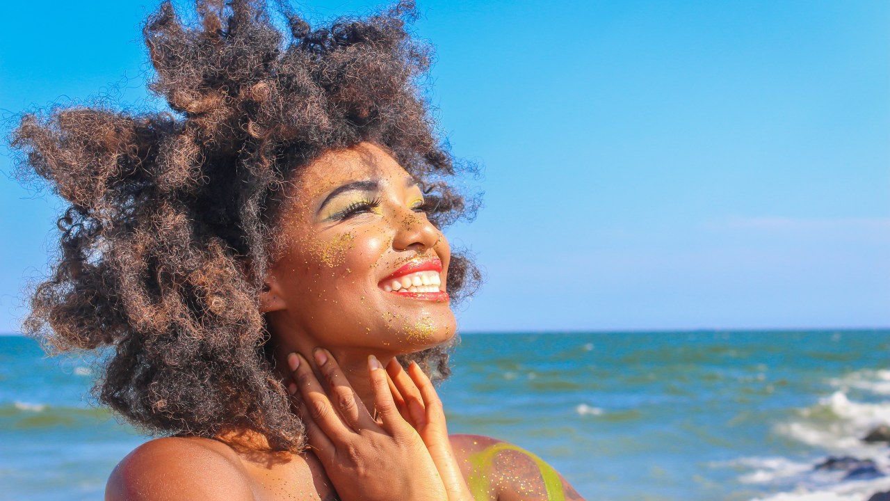 Imagem ilustrativa de uma mulher sorrindo na praia