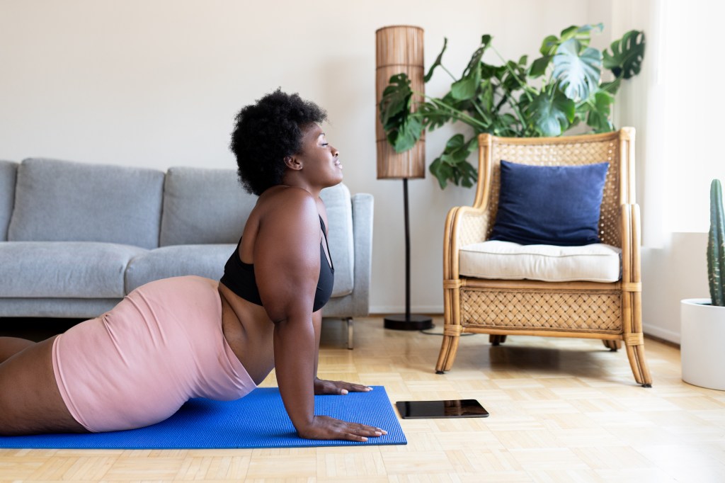 Mulher fazendo yoga em casa em um tapete