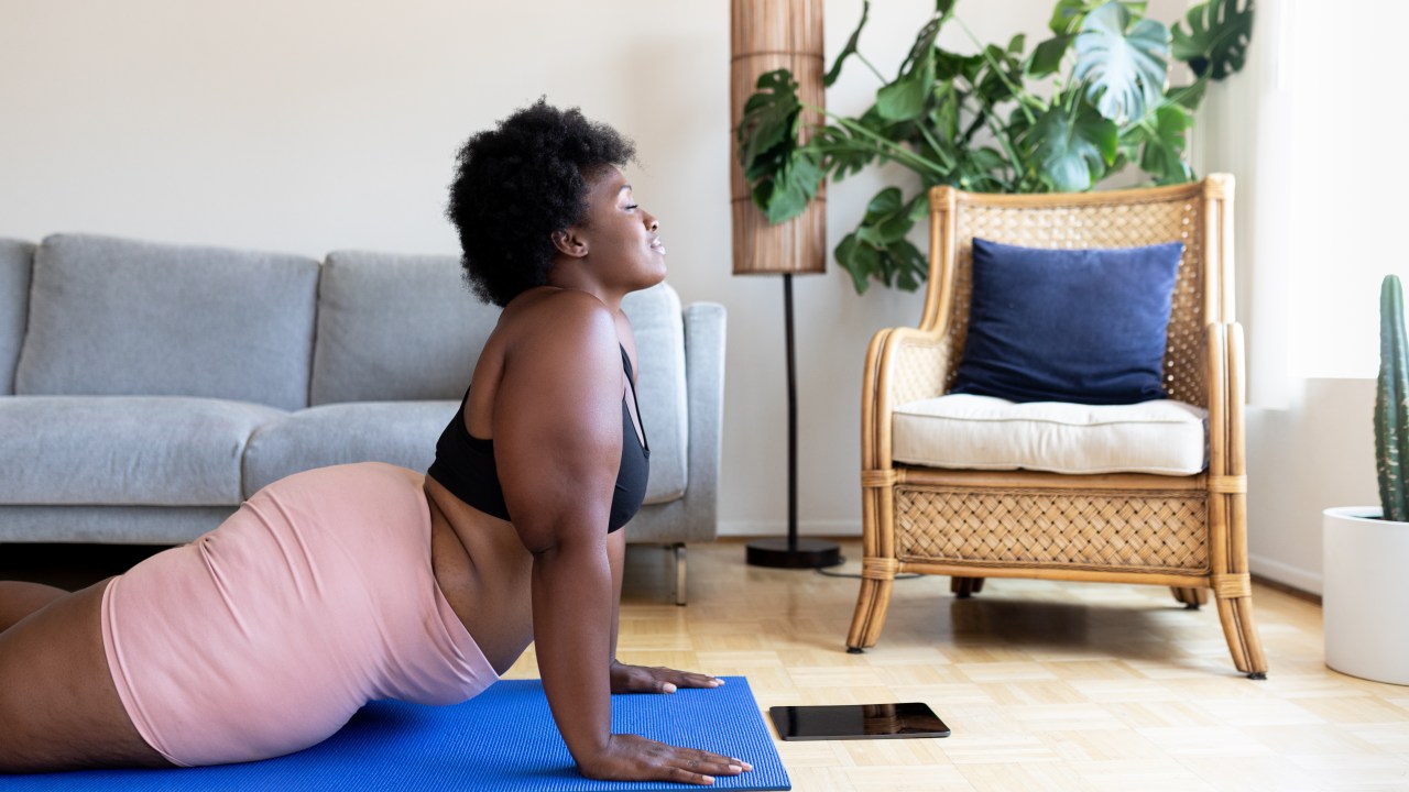 Mulher fazendo yoga em casa em um tapete