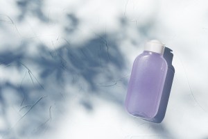 Bottle of micelar water or tonic, product for skincare beautyon textured concrete background with shadows.