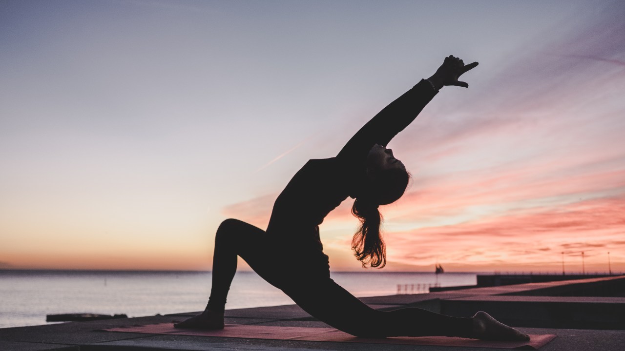 silueta feminia praticando yoga ao pôr do sol