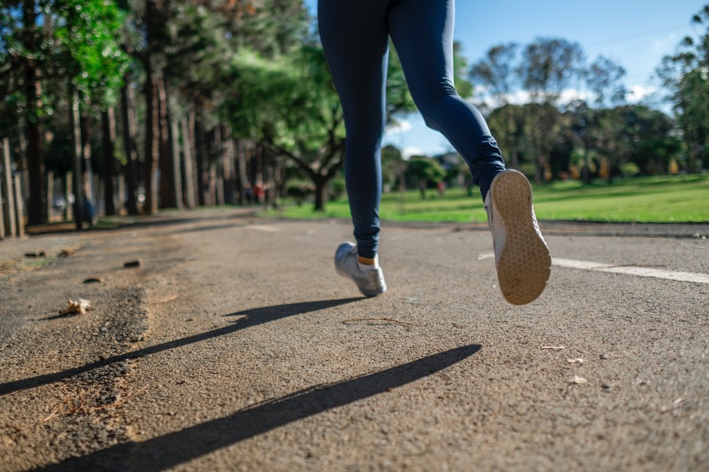 Mulher correndo na rua, em praça - Correr na esteira: Quais as diferenças do asfalto?