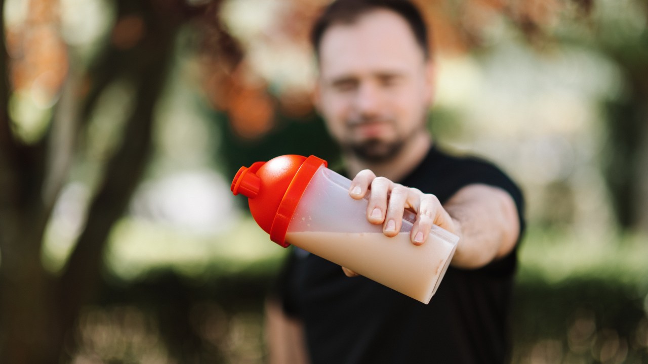 homem segurando uma garrafa de shake em um parque
