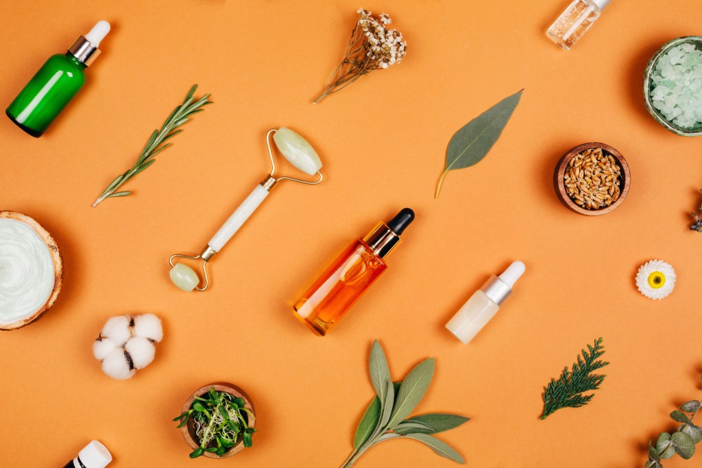 Modern apothecary with natural ingredients produtos de skin care posicionados deitados na diagonal contra fundo laranja
