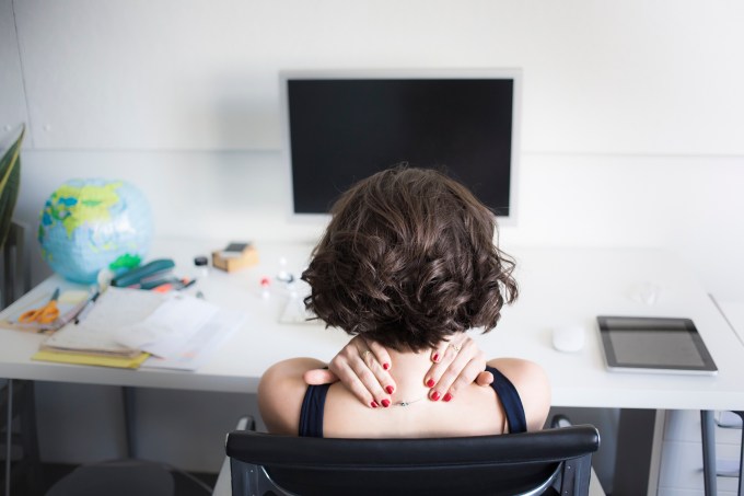 Young woman massaging her neck at desk