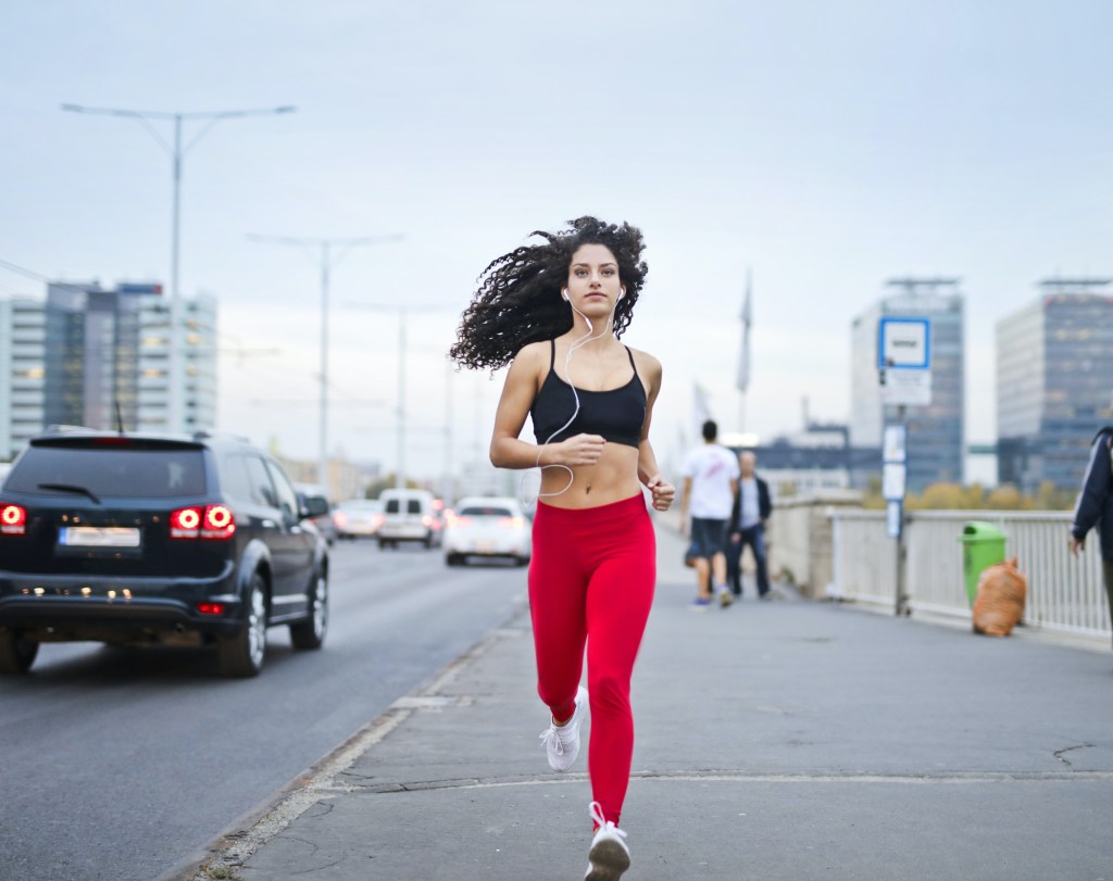 mulher correndo na rua, se exercitando, com fones de ouvido