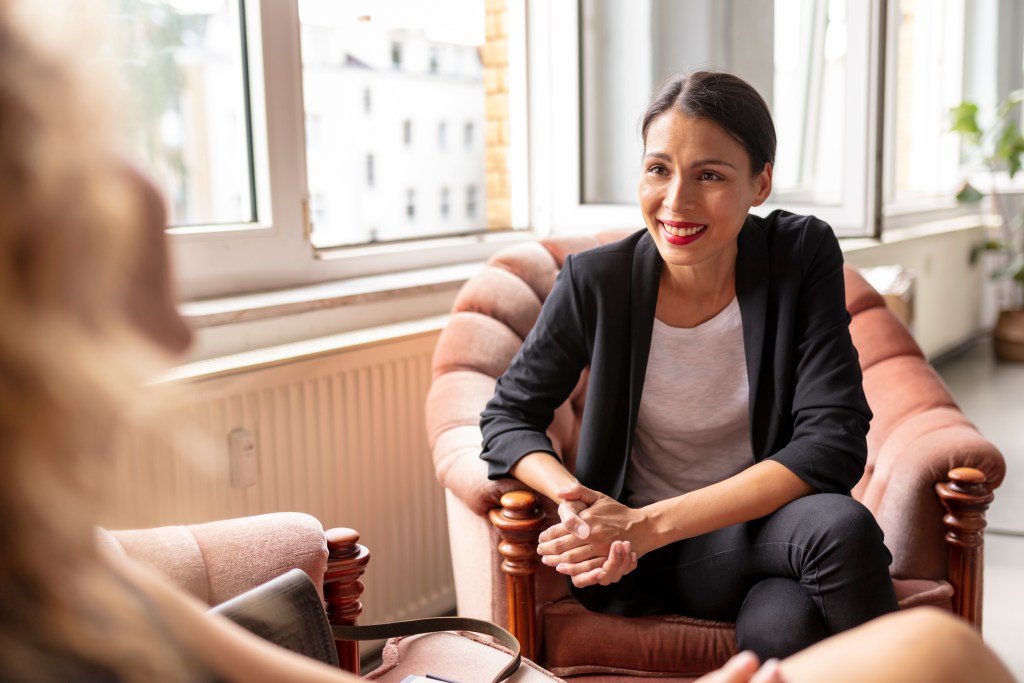 young female adult are talking with her co-worker síndrome do impostor