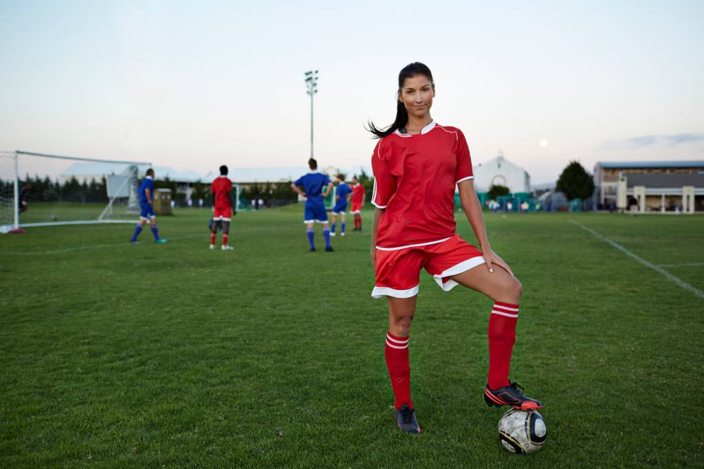 Female soccerplayer standing with foot on the ball