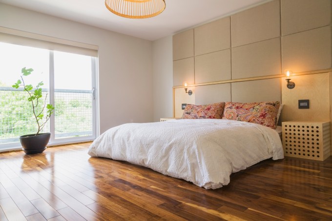 King size bed in bedroom with American walnut hardwood flooring on the upstairs floor inside a modern cube style home, Quebec, Canada