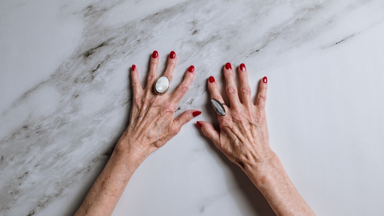 mão de uma senhora branca com as unhas pintadas de vermleho