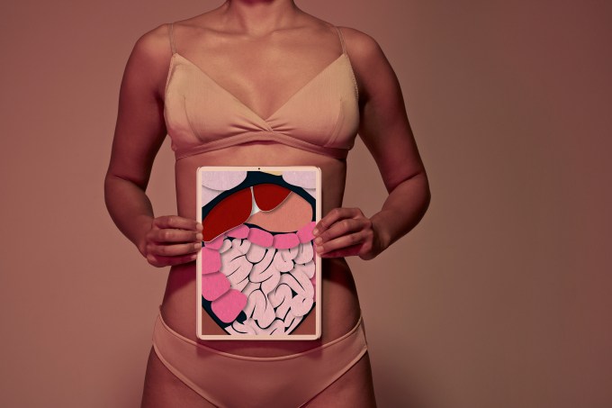 Young woman holding tablet in front of stomach to show intestines