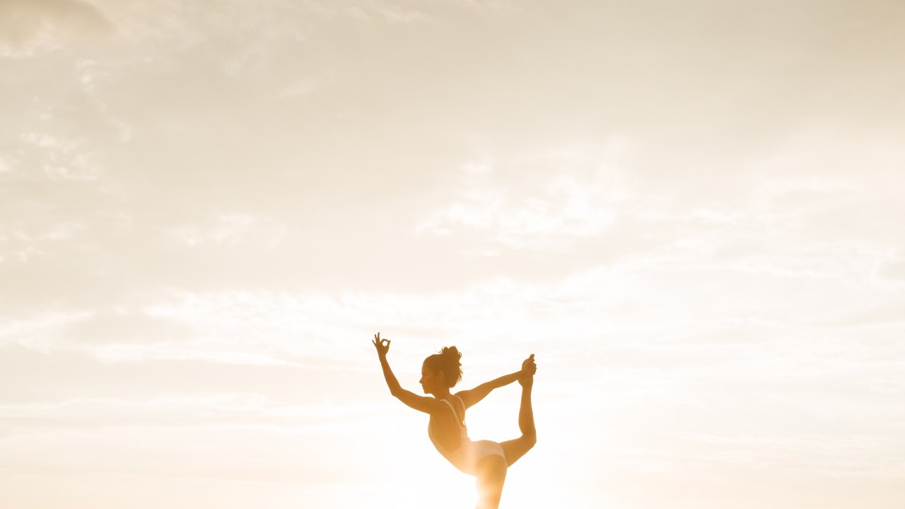 Mulher posando em movimento de yoga ao por do sol