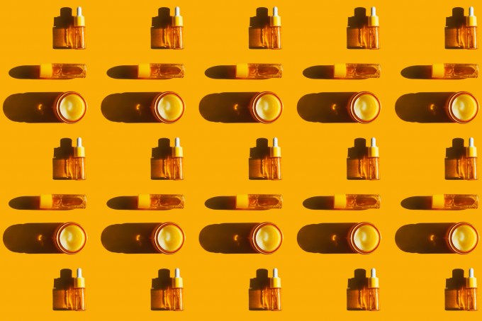 Pattern made of many glass bottles with face serums and glass jars with creams on bright yellow background with shadows. Polyglutamic acid is new hyaluronic acid. Concept of body care and beauty. Flat lay style