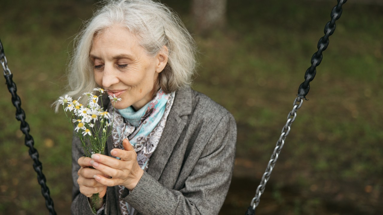 senhora de idade cheirando flores