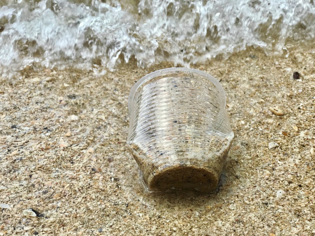 copo plástico na areia da praia