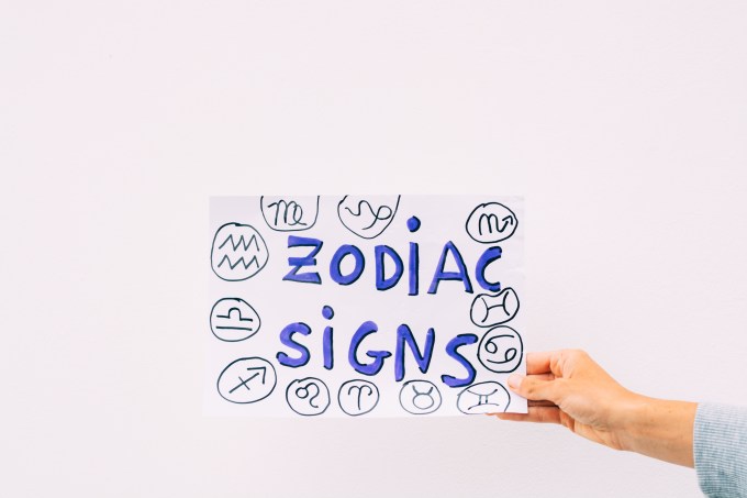 young woman’s hand holding a sign with the words zodiac sign with white background