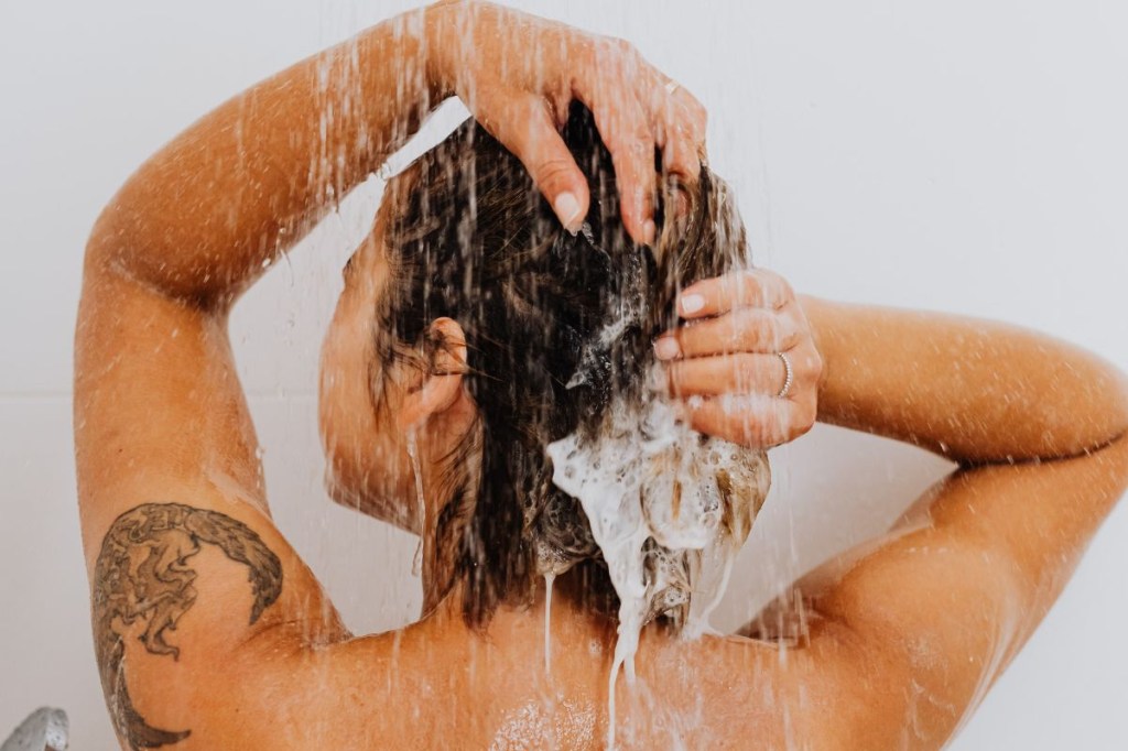 Mulher de costas lavando o cabelo